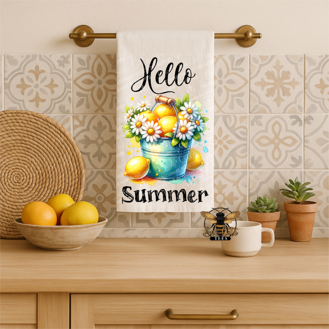Kitchen towel with 'Hello Summer' text and lemon design hanging on a towel rack.