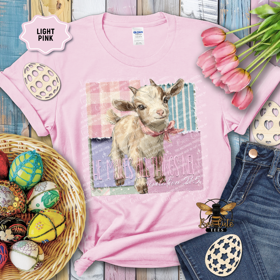 Pink t-shirt with a goat graphic and text, surrounded by Easter decorations on a wooden surface.
