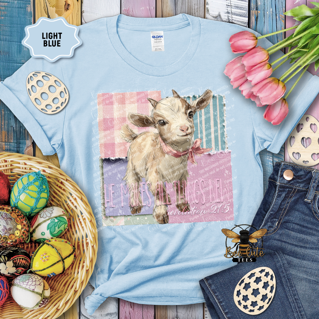 Light blue t-shirt with a goat graphic and text, surrounded by Easter decorations on a wooden surface.
