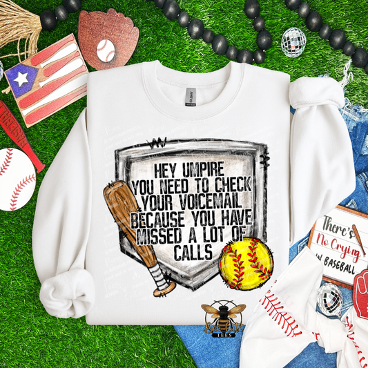 White sweatshirt with sports-themed design on grass with sports equipment