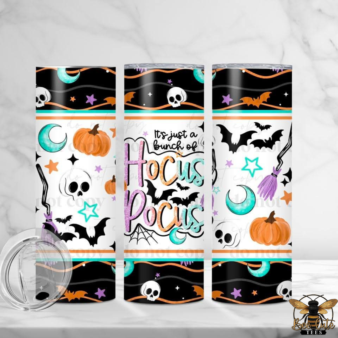 Three tall skinny tumblers with a Halloween-themed wrap design are displayed on a white marble surface. The design features black borders, white skulls, orange pumpkins, teal moons, purple broomsticks, and the text 'It's just a bunch of Hocus Pocus'.