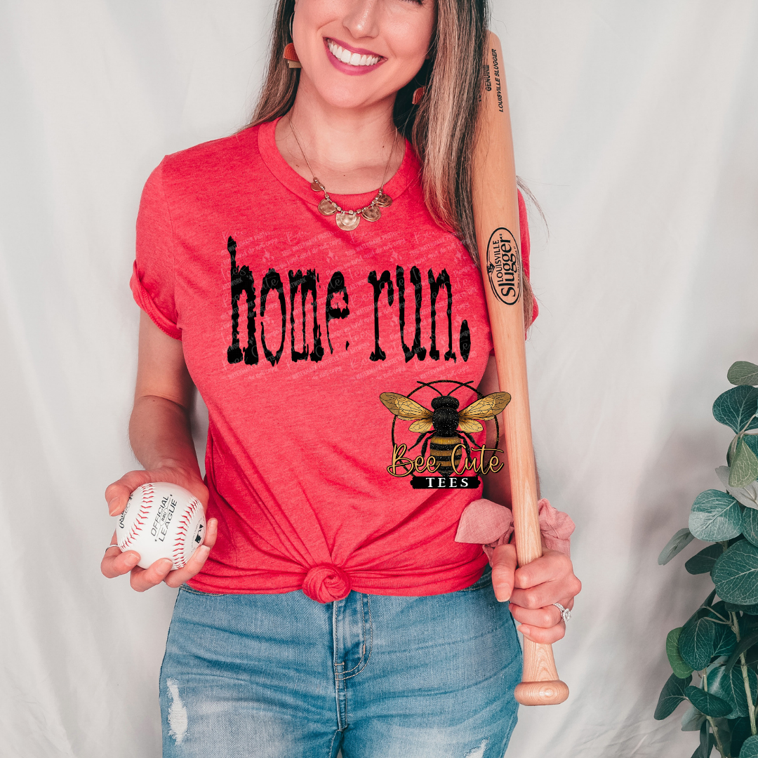 Woman wearing a red 'home run' t-shirt holding a baseball and bat against a white background