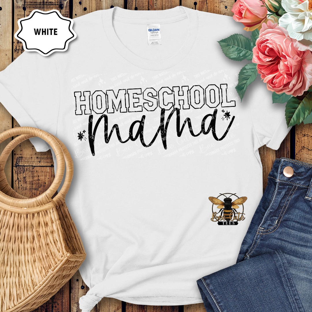 White t-shirt with 'Homeschool Mama' text on a wooden surface with flowers and denim jeans.