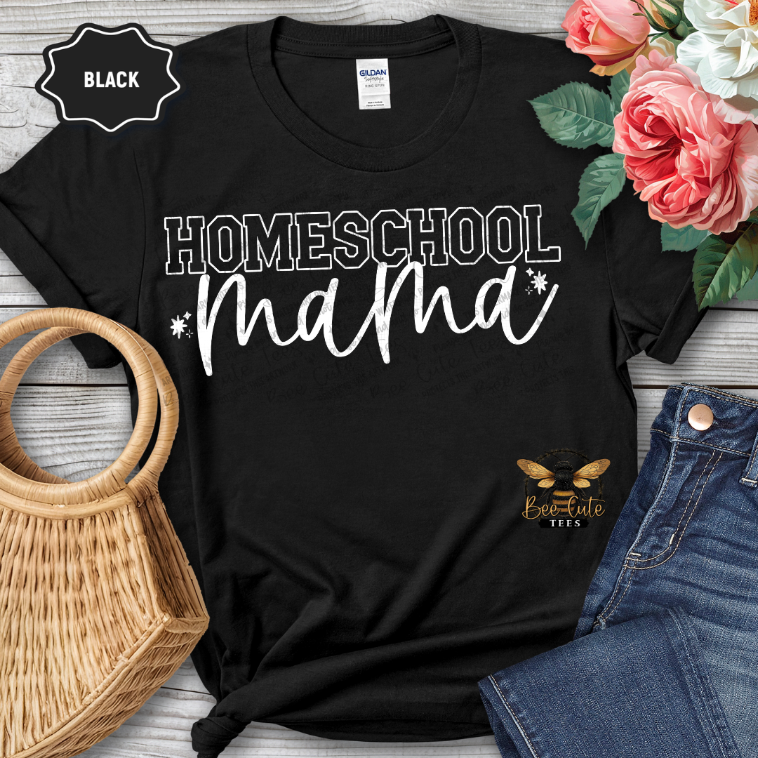 Black t-shirt with 'Homeschool Mama' text and bee logo, placed on a wooden surface with flowers and jeans.