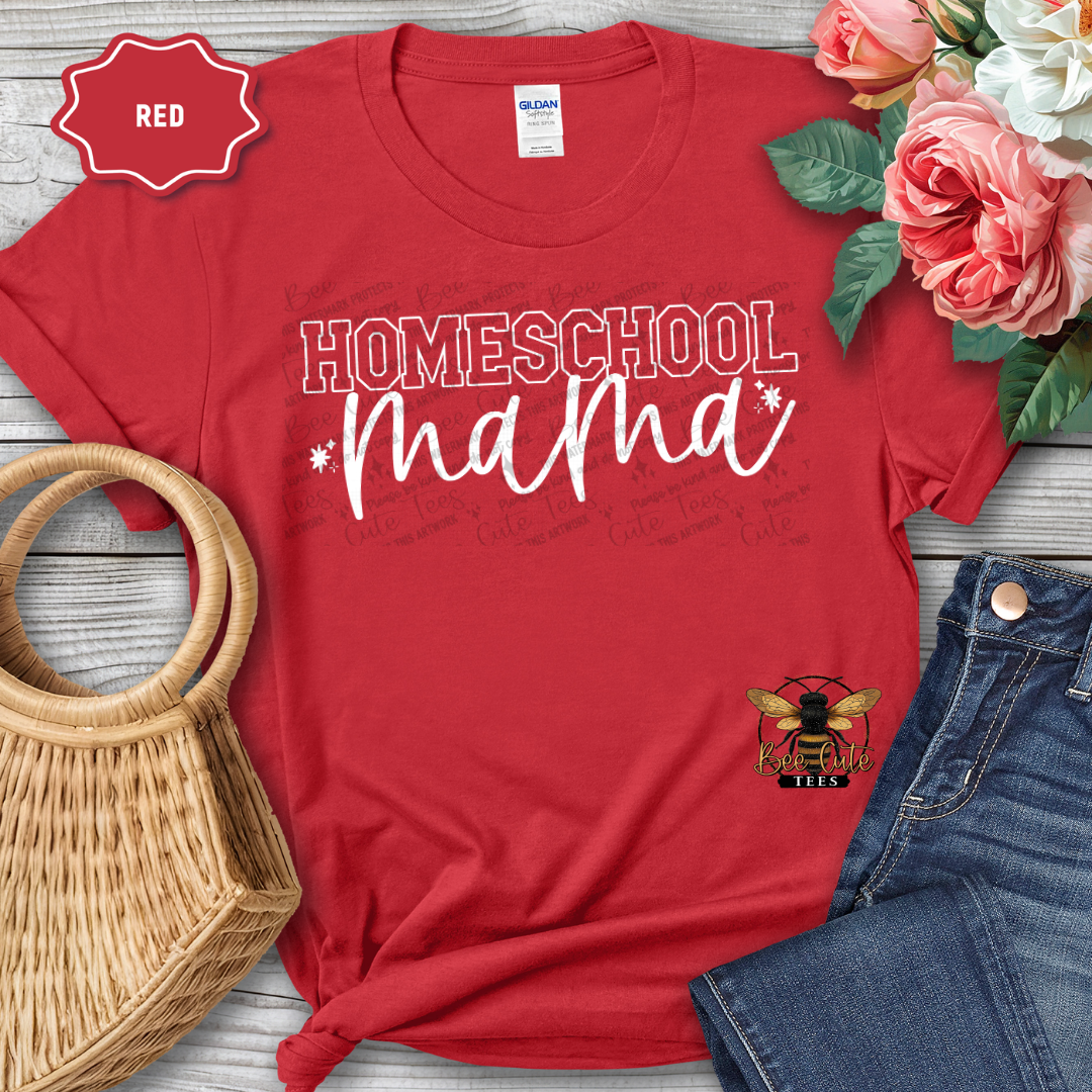 Red t-shirt with 'Homeschool Mama' text and bee logo, placed on a wooden surface with flowers and jeans.