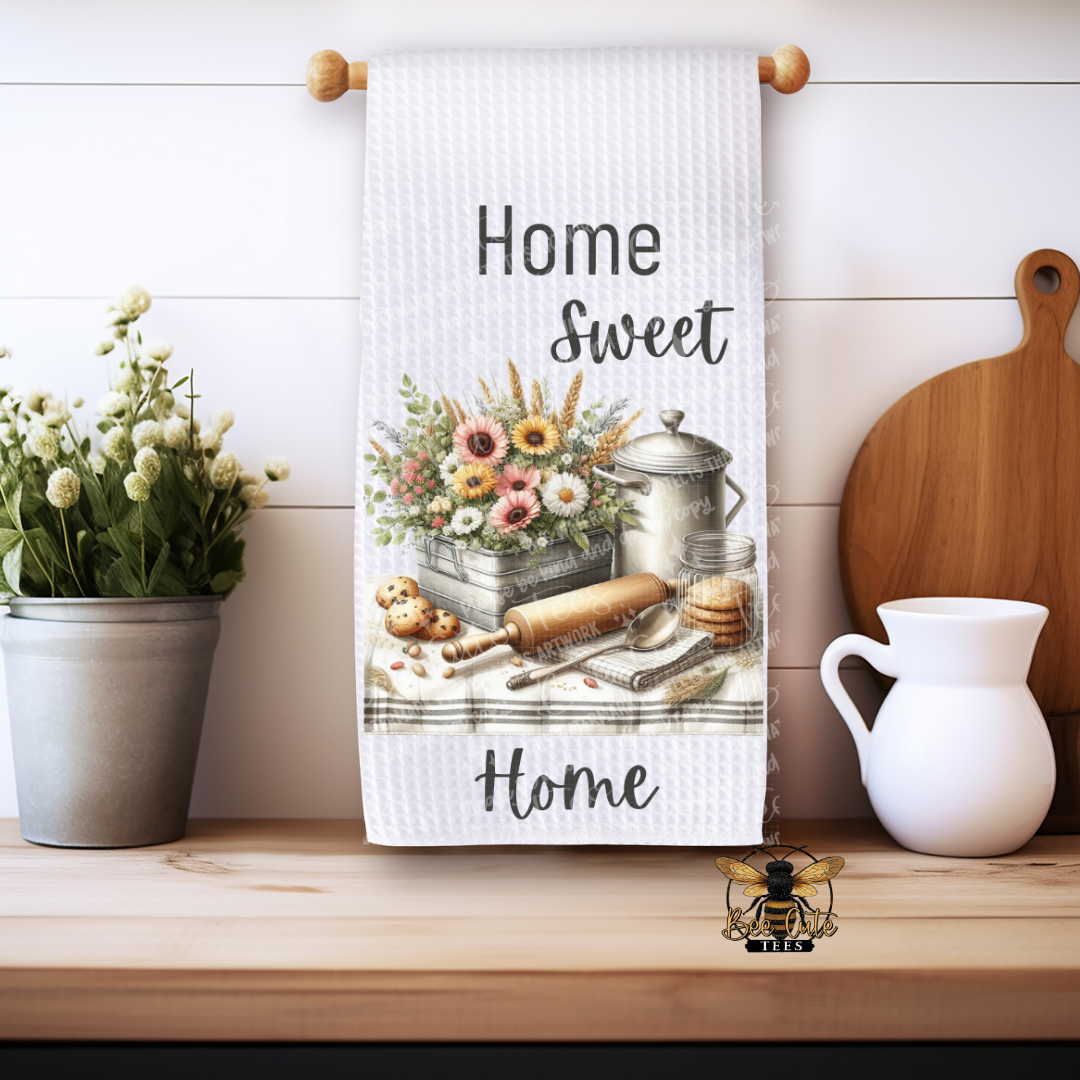 Kitchen towel with 'Home Sweet Home' text and floral design on a wooden shelf.