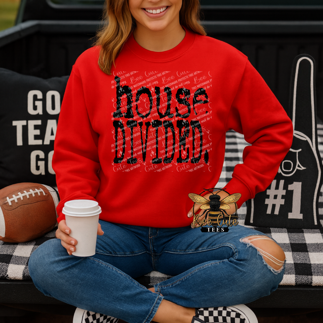 Red crewneck sweatshirt featuring distressed black “house divided.” text, shown on a model sitting with a football and coffee, styled for a cozy game day look.
