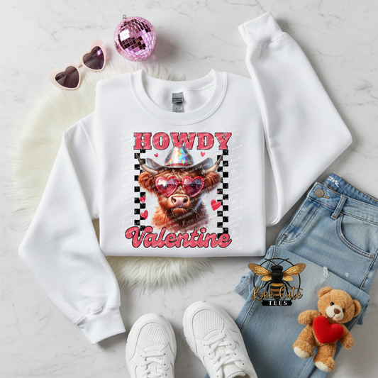 White sweatshirt with a cow graphic and 'Howdy Valentine' text, surrounded by denim shorts, white sneakers, and a teddy bear.