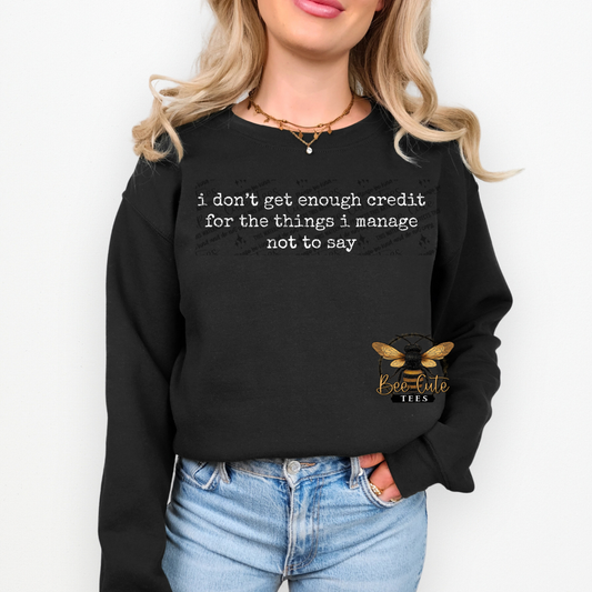 Person wearing a black sweatshirt with text and a logo, standing against a white background