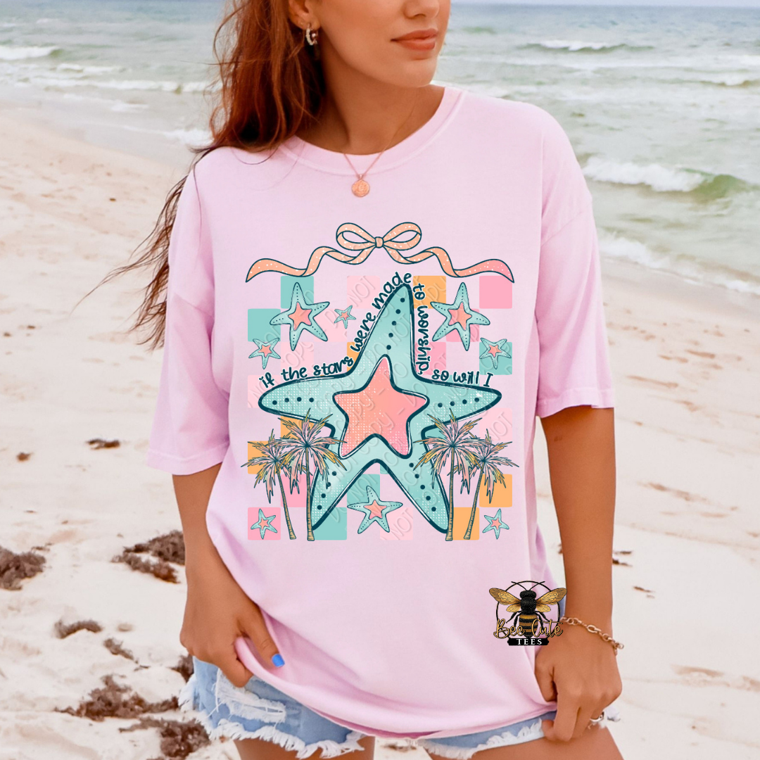 Person wearing a pink t-shirt with a starfish design on a beach