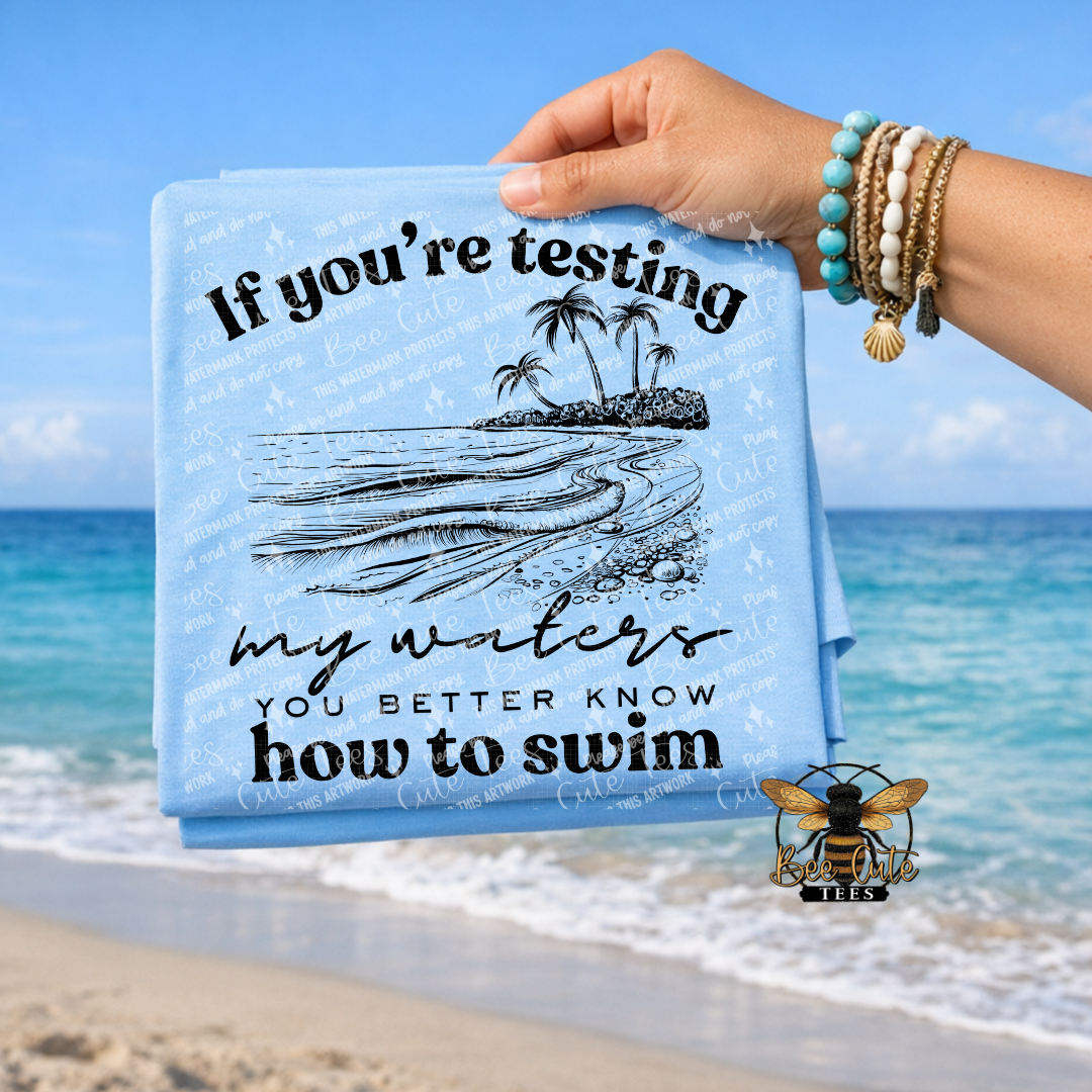 Hand holding a t-shirt with a beach design and text against a beach background