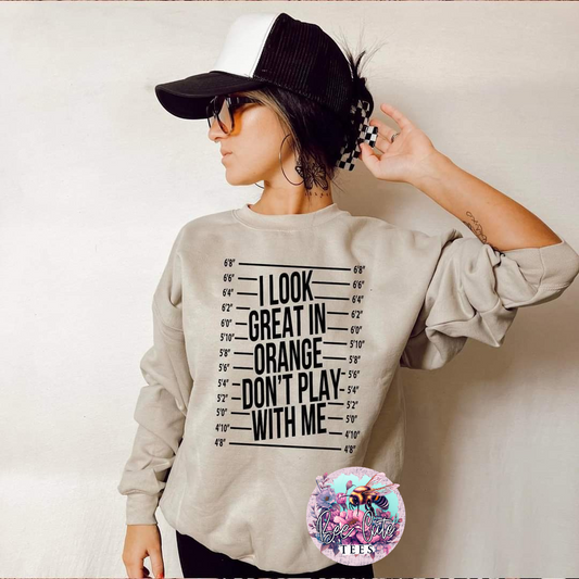 Person wearing a beige sweatshirt with text and a black cap, against a plain background.