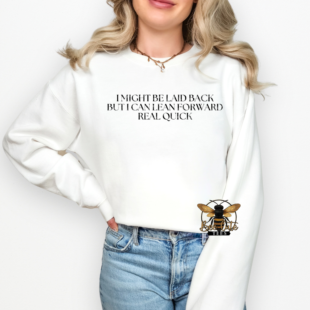 Person wearing a white sweatshirt with text and a logo, standing against a plain background