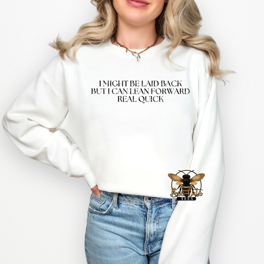 Person wearing a white sweatshirt with text and a logo, standing against a plain background