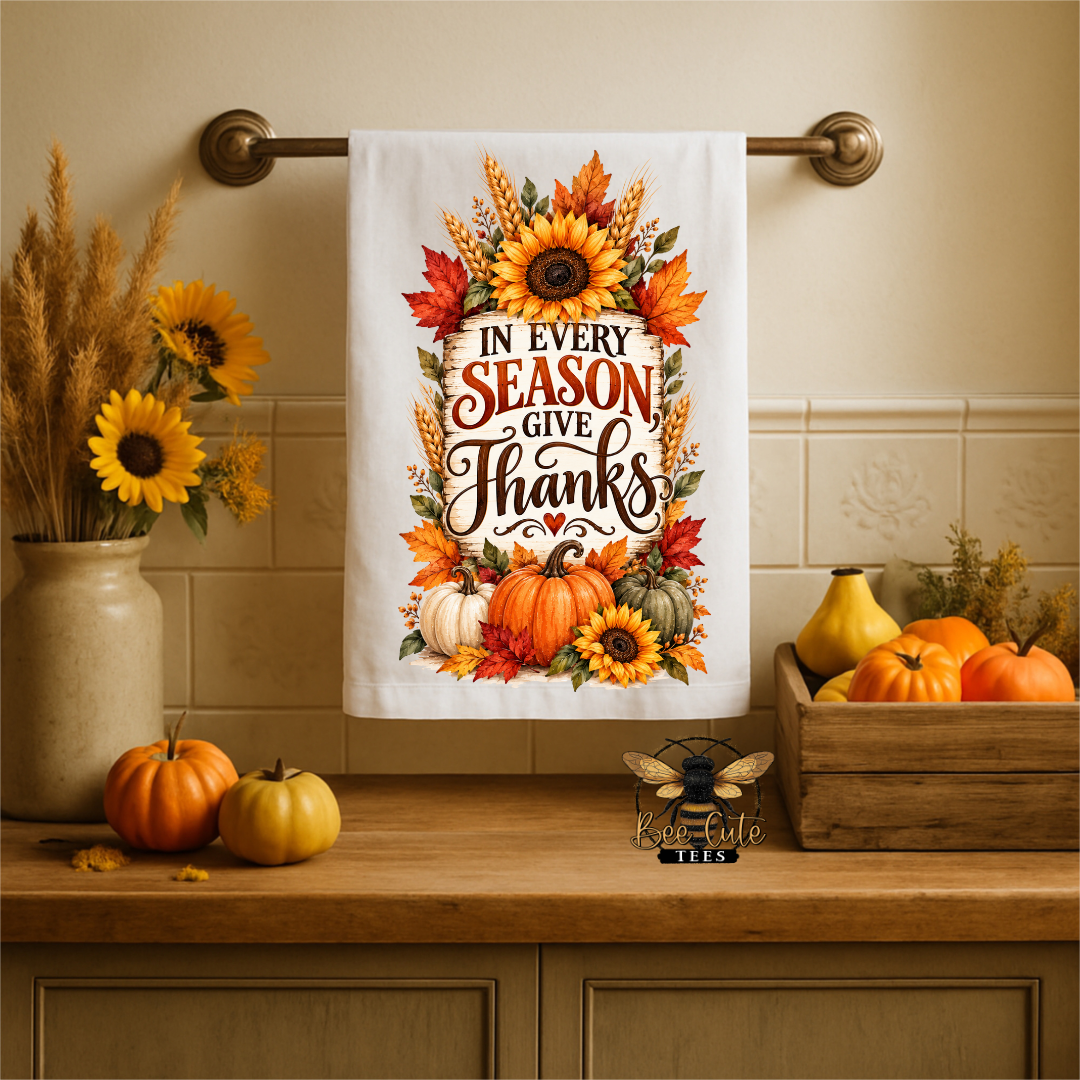 A white kitchen towel with a colorful autumn 'Thanksgiving' quote hangs on a brass towel bar. The towel features sunflowers, pumpkins, and fall leaves.