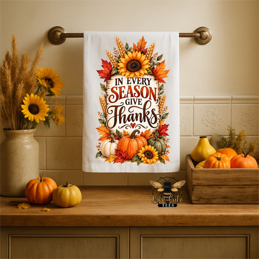 A white kitchen towel with a colorful autumn 'Thanksgiving' quote hangs on a brass towel bar. The towel features sunflowers, pumpkins, and fall leaves.