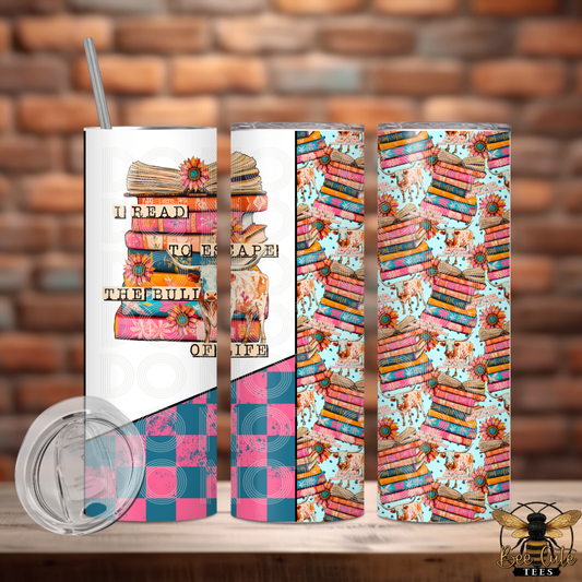 Tumbler with book-themed design and text on a wooden surface with brick wall background
