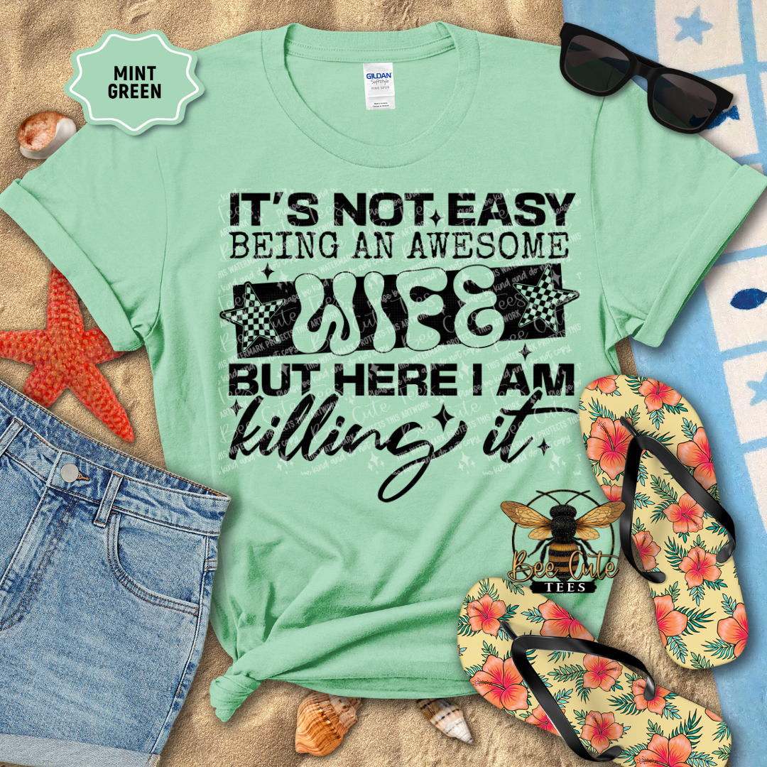 Mint green t-shirt with humorous text design on a beach-themed background with flip-flops and sunglasses.