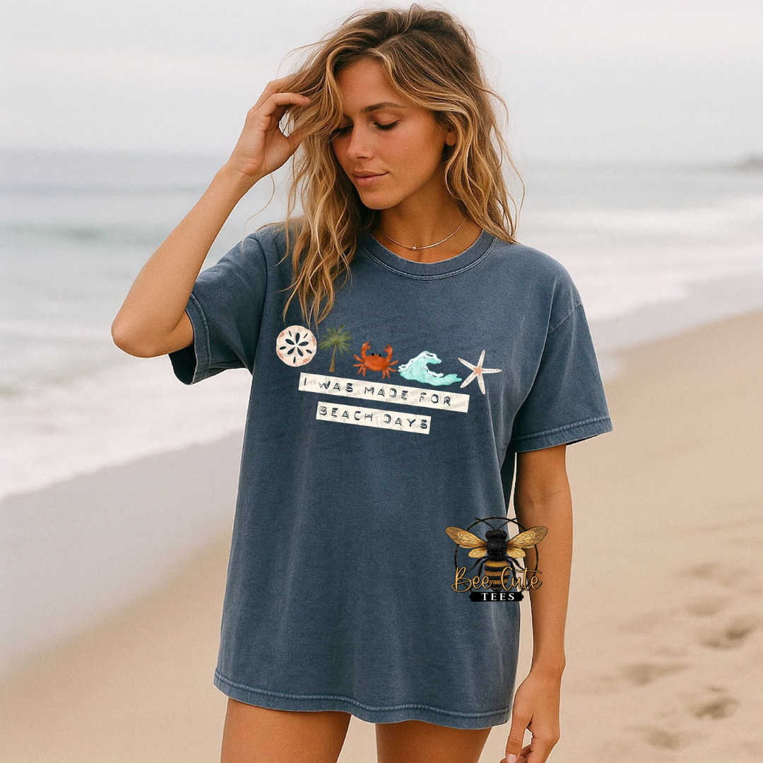 Woman wearing a blue t-shirt with beach-themed graphics on a beach.