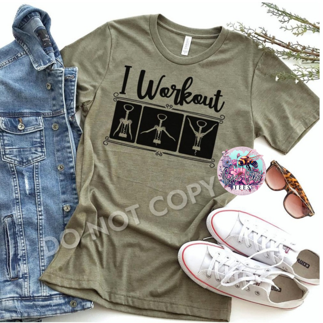 Olive green t-shirt with 'I Workout' graphic, denim jacket, white sneakers, and sunglasses on a white background.