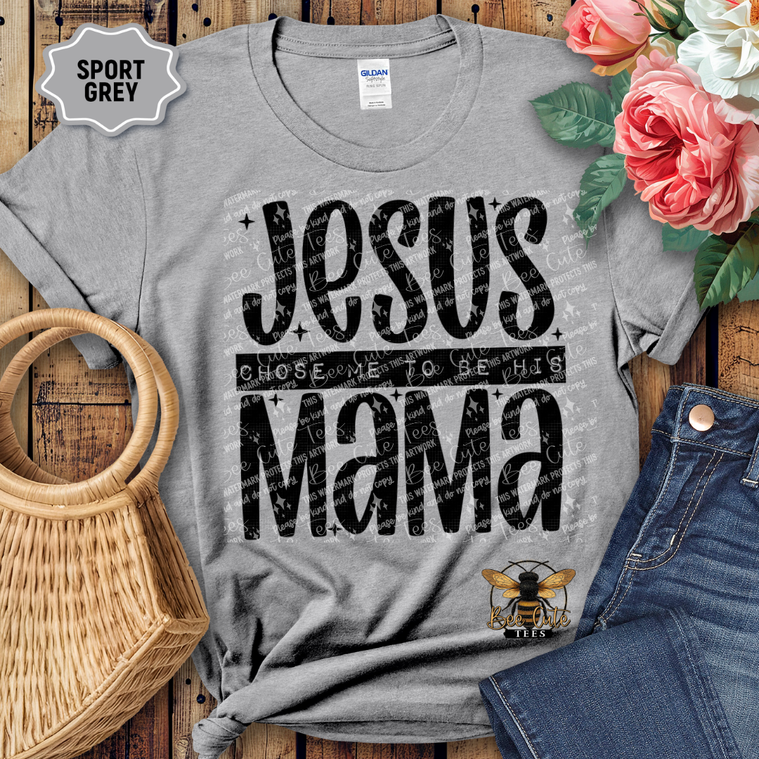 Gray t-shirt with 'Jesus Chose Me to be His Mama' text on a wooden surface with flowers and jeans.