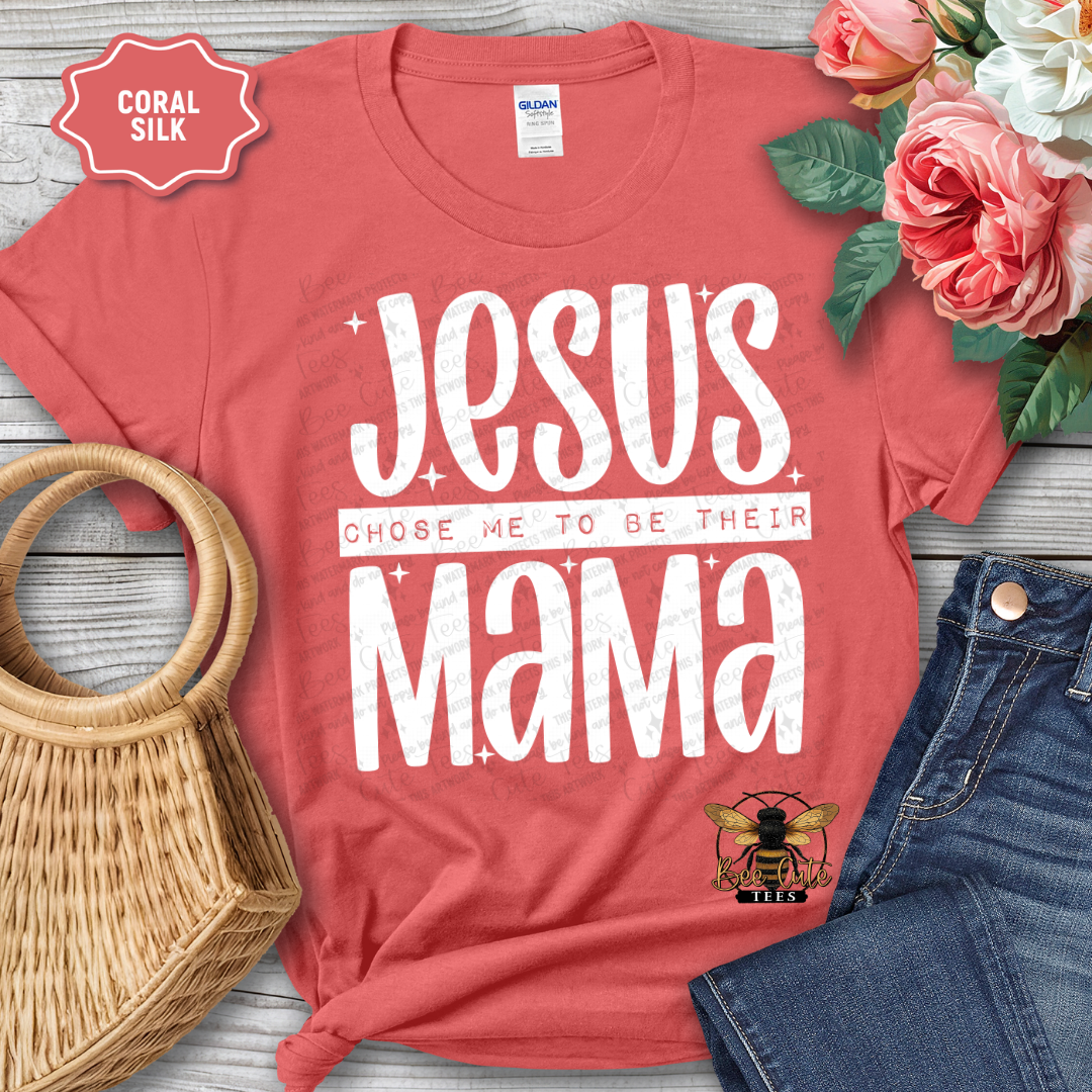 Red t-shirt with 'Jesus chose me to be their mama' text, surrounded by flowers and denim jeans on a wooden surface.