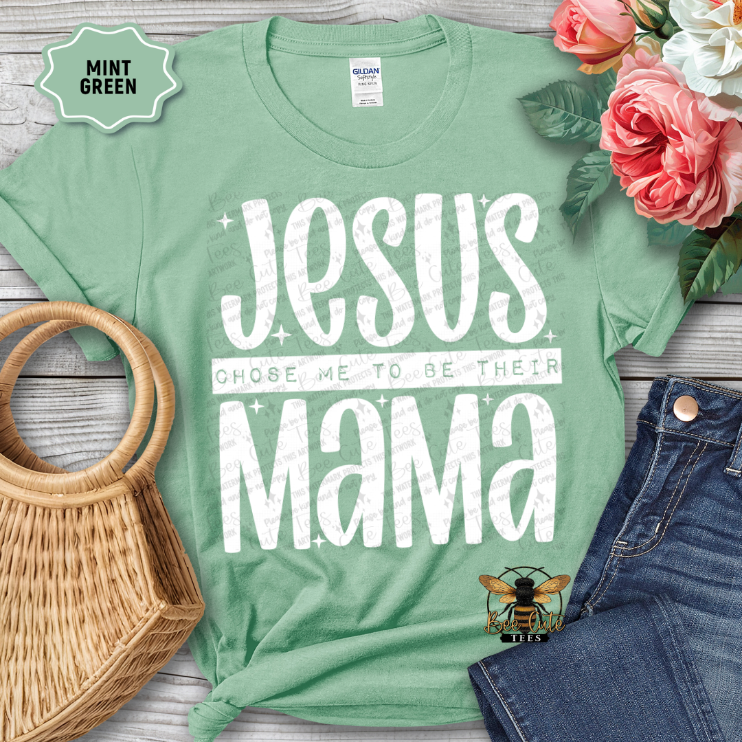 Mint green t-shirt with 'Jesus chose me to be their mama' text, surrounded by flowers and accessories on a wooden surface.