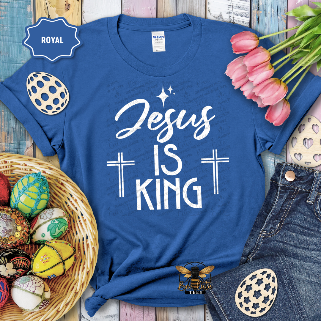 Blue t-shirt with 'Jesus is King' text, surrounded by Easter decorations on a wooden surface.