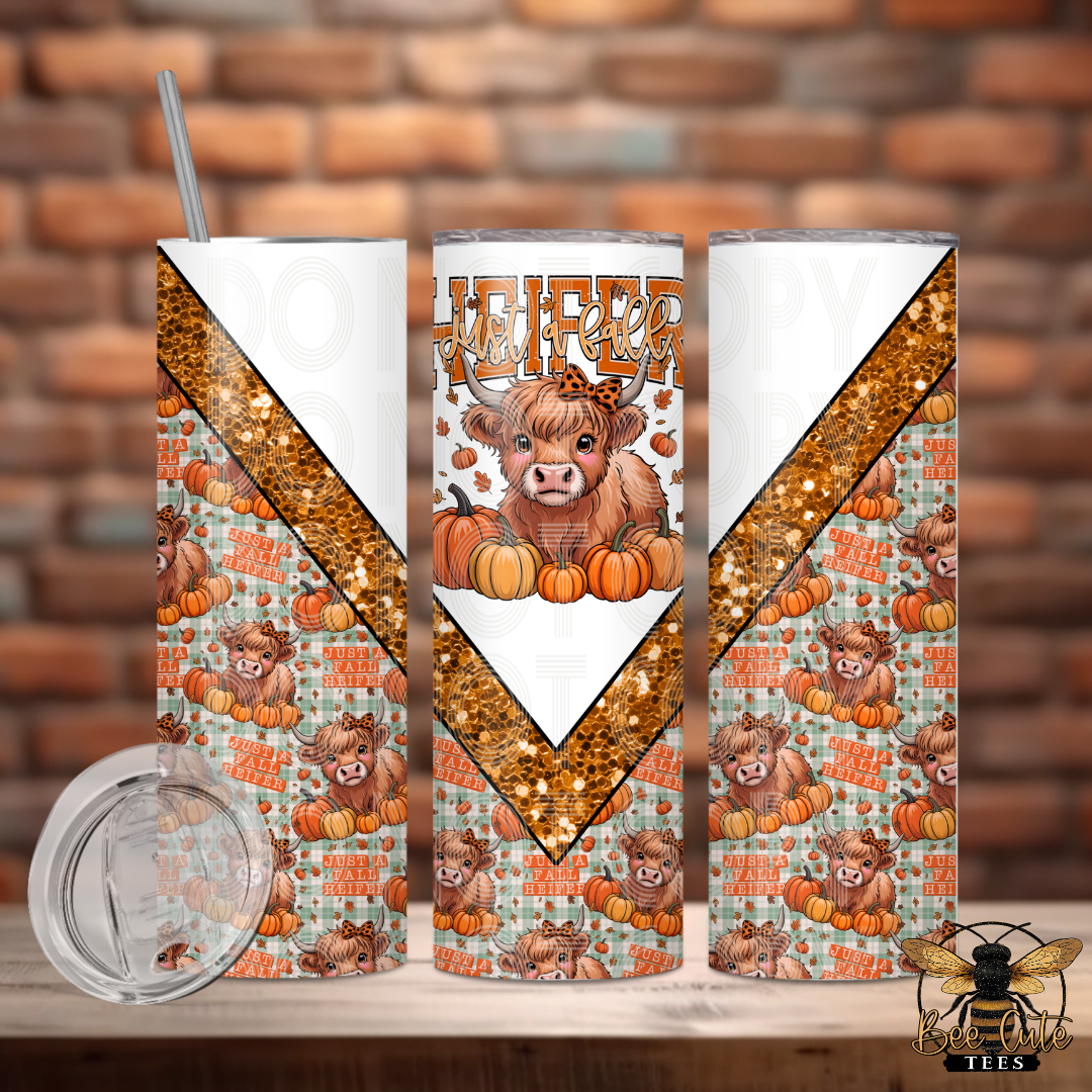 Three tall skinny tumblers with a fall harvest theme, featuring a highland cow, pumpkins, and autumn leaves, displayed on a wooden surface with a brick wall background. A clear lid and a metal straw are shown in the foreground.