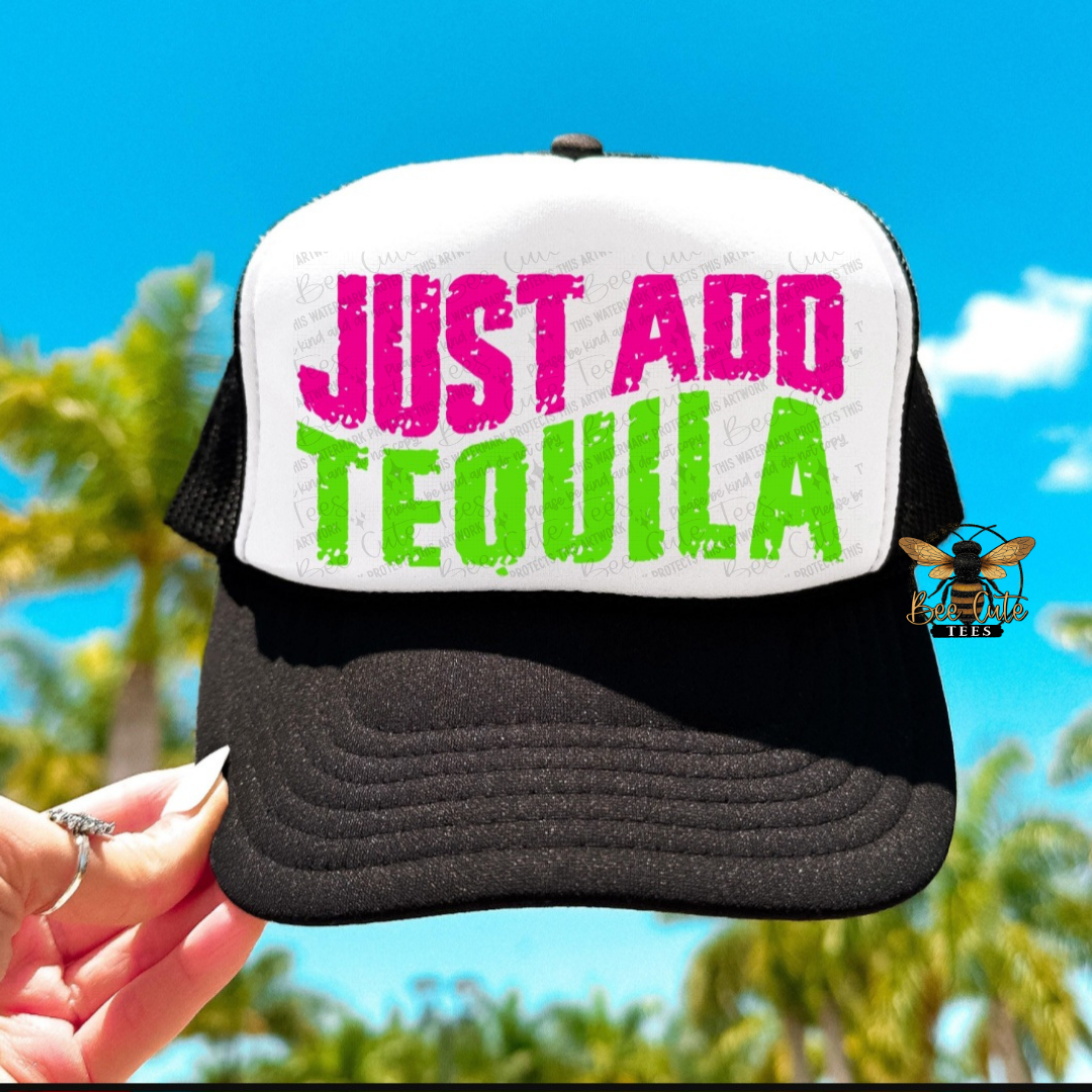 Trucker hat with 'Just Add Tequila' text held against a blue sky and palm tree background