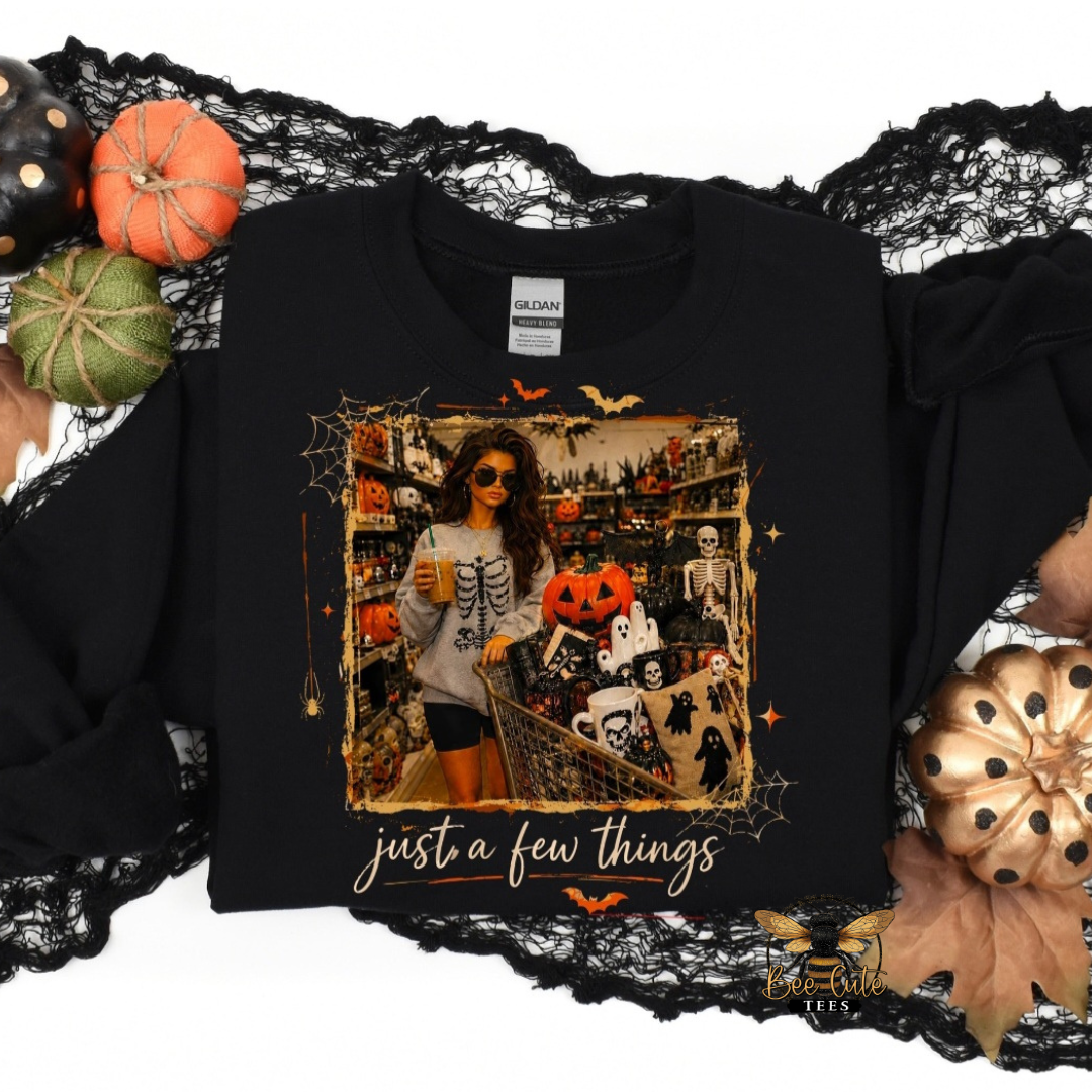A black long-sleeve graphic sweatshirt with a Halloween-themed photo print and the text 'just a few things' in white script. The sweatshirt is styled with black lace, pumpkins, and autumn leaves on a white background.