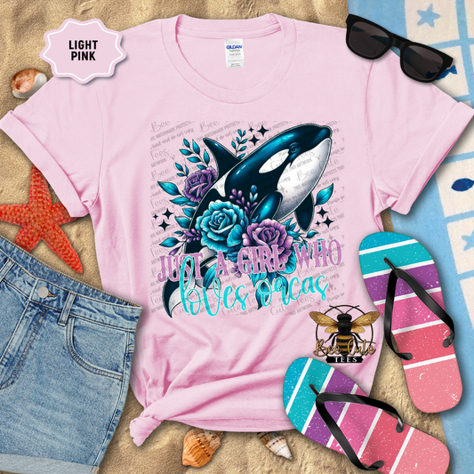 Light pink t-shirt with a whale design and text, surrounded by beach accessories.