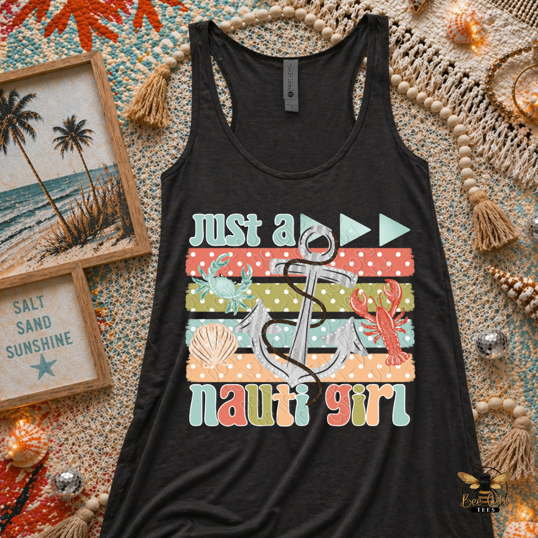 Black tank top with 'Just a nauti girl' design on a textured surface with beach-themed decor.
