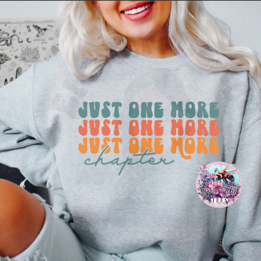 Person wearing a gray sweatshirt with colorful text and a logo in the corner.