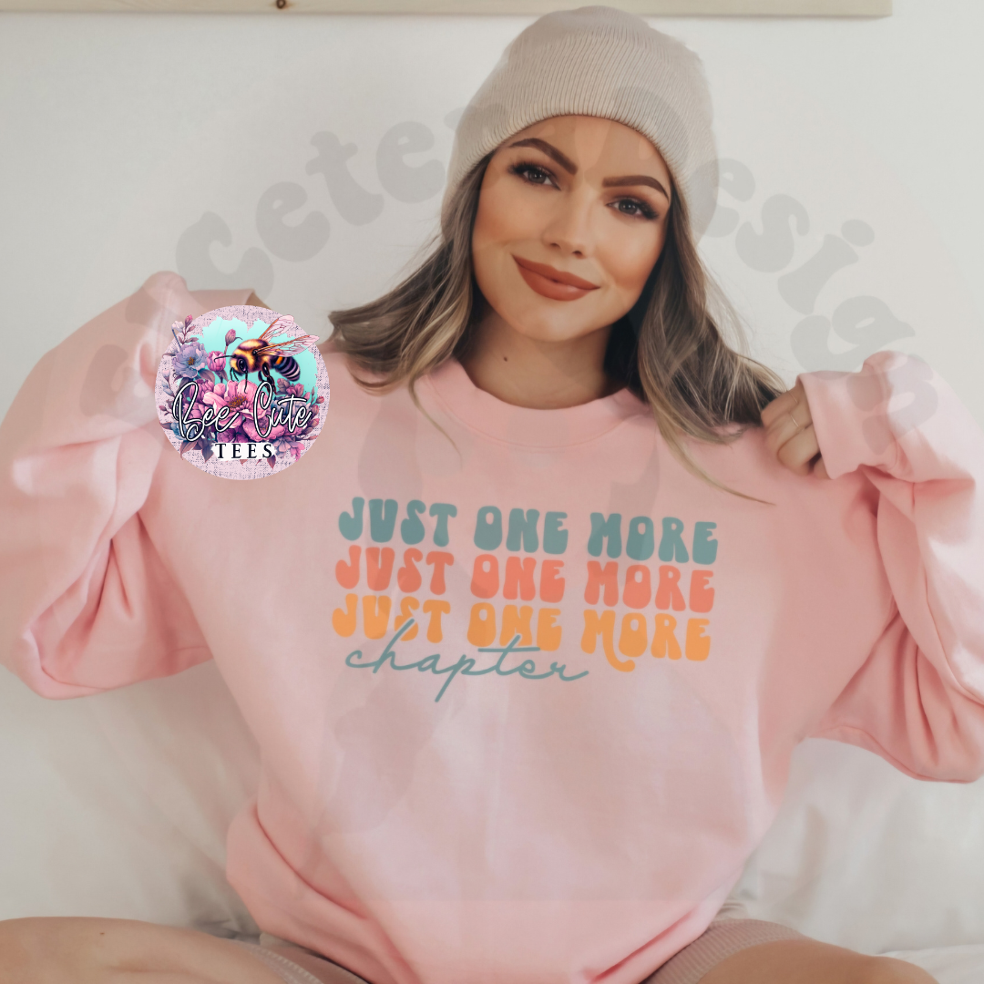 Person wearing a pink sweatshirt with colorful text, sitting on a white couch.