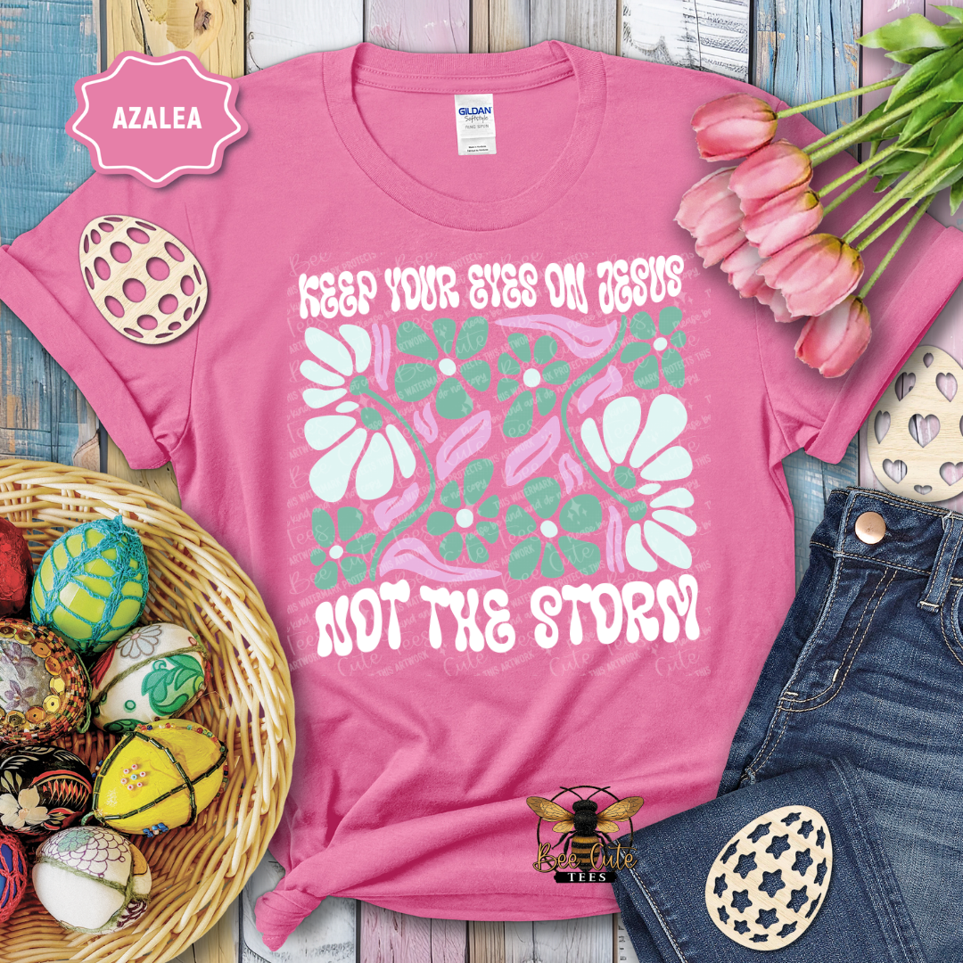 Pink t-shirt with floral design and text, surrounded by Easter decorations on a wooden surface.
