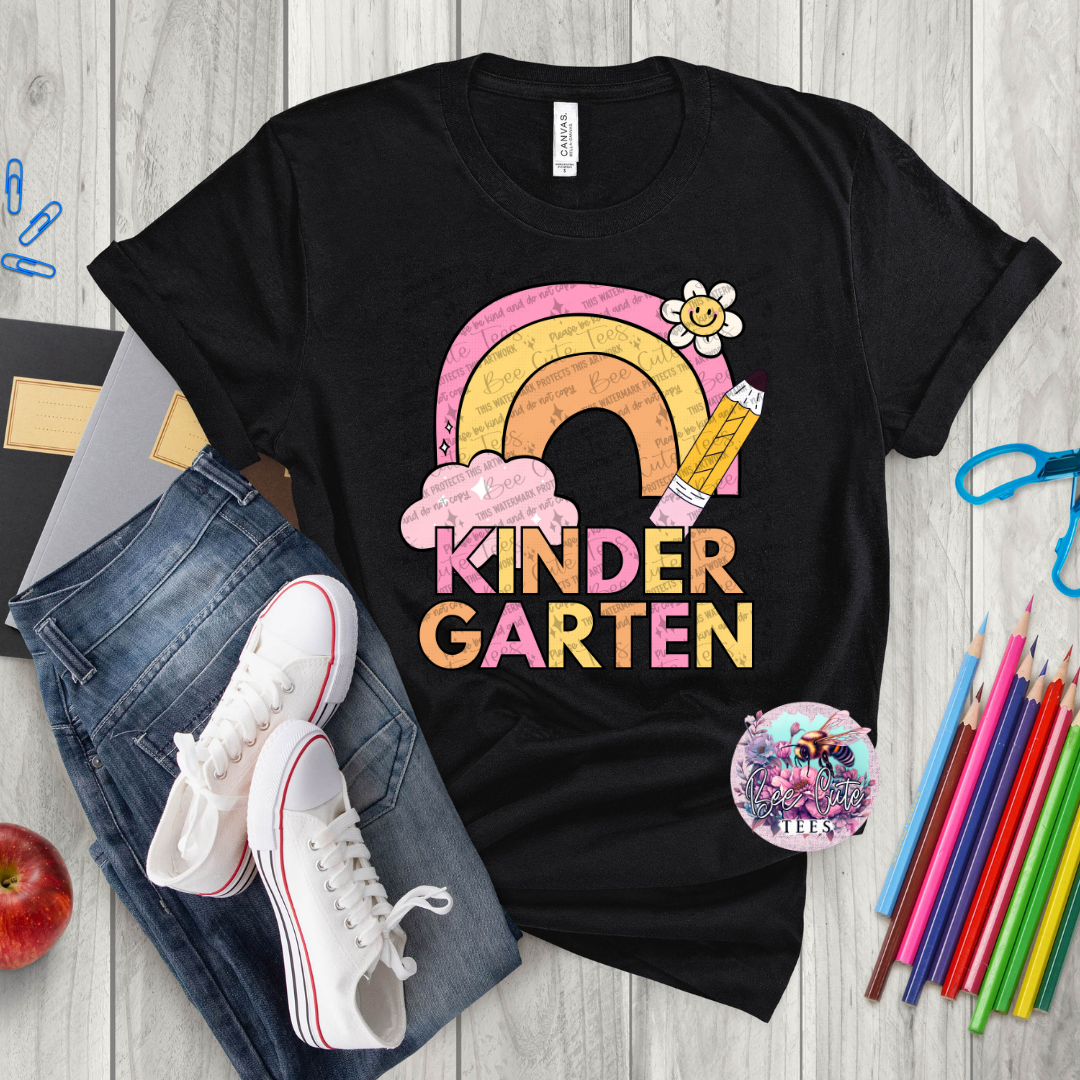 Black t-shirt with 'KinderGarten' design on a wooden surface with school supplies.