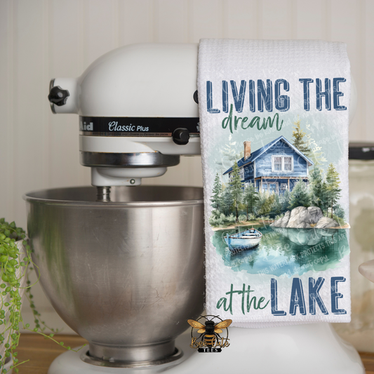 Kitchen mixer with a towel featuring a lake scene and text 'Living the dream at the Lake' on a kitchen counter.