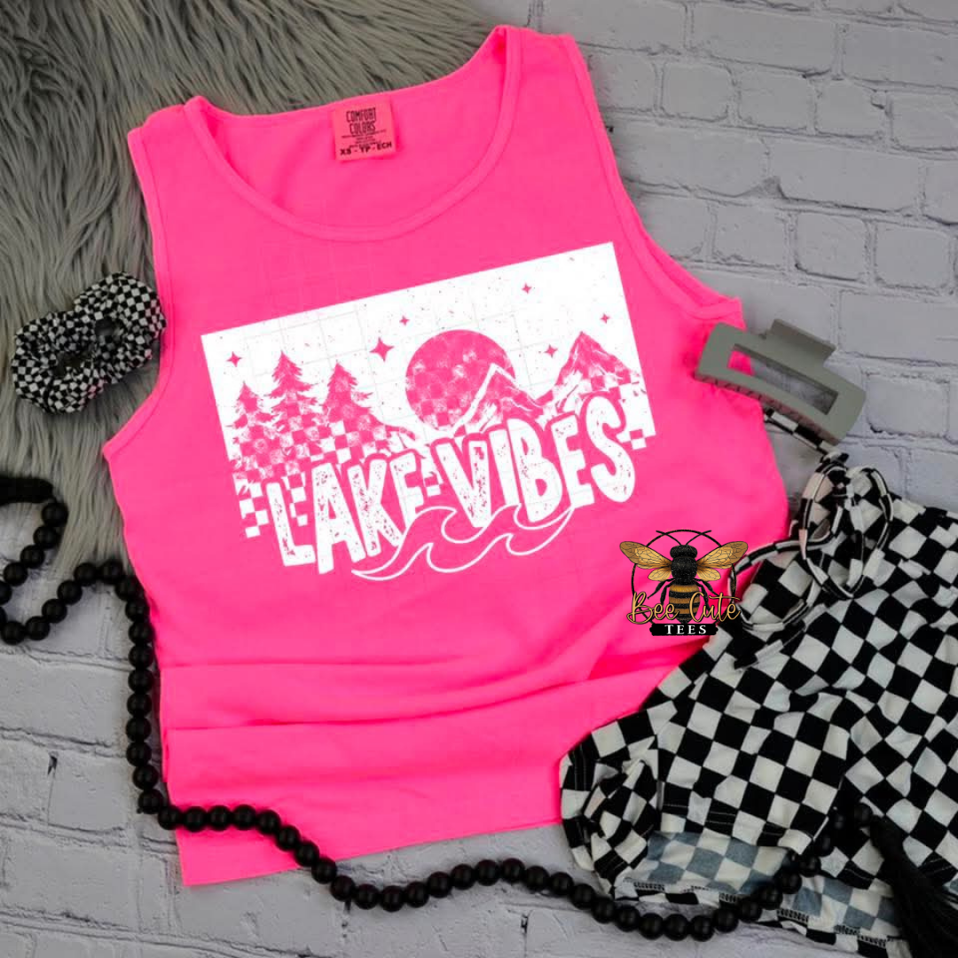 Pink tank top with 'Lake Vibes' design on a gray surface with accessories.