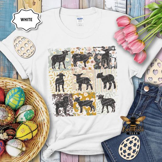 White t-shirt with black sheep design on a wooden surface with Easter decorations.
