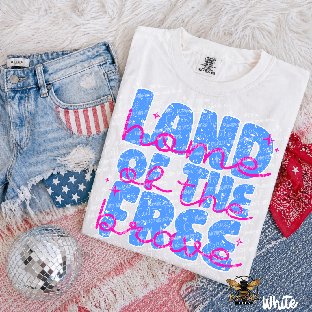 White t-shirt with colorful text design on a textured surface with denim shorts and disco ball.