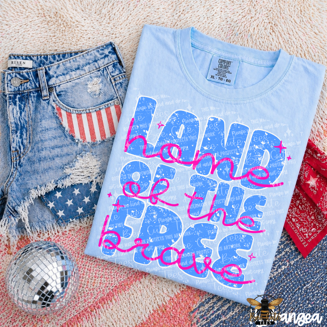 Light blue t-shirt with 'Land of the Free because of the Brave' text, denim shorts, and red bandana on a textured surface.