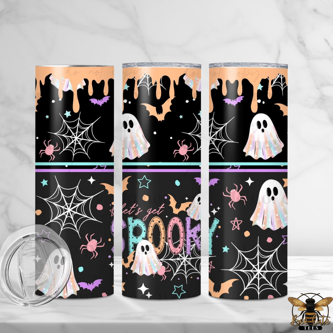 Three tall insulated tumblers with Halloween-themed wraparound prints are shown on a light marble surface and background. The designs feature black backgrounds with white ghosts, orange bats and stars, purple spiders, white spiderwebs, and the words 'Let's get SPookty' in pastel colors.