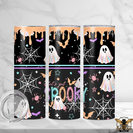 Three tall insulated tumblers with Halloween-themed wraparound prints are shown on a light marble surface and background. The designs feature black backgrounds with white ghosts, orange bats and stars, purple spiders, white spiderwebs, and the words 'Let's get SPookty' in pastel colors.