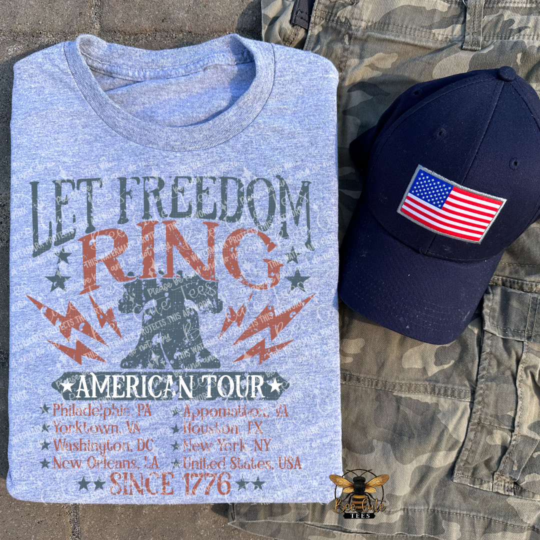 Blue t-shirt with 'Let Freedom Ring' text and a cap with an American flag on camouflage pants.