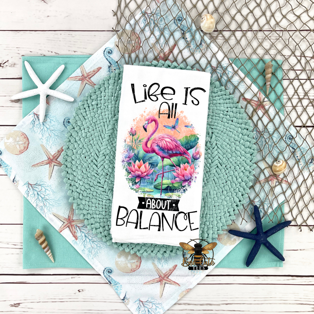 Tea Towel with flamingo design and 'Life is all about balance' text on a textured surface with decorative elements.