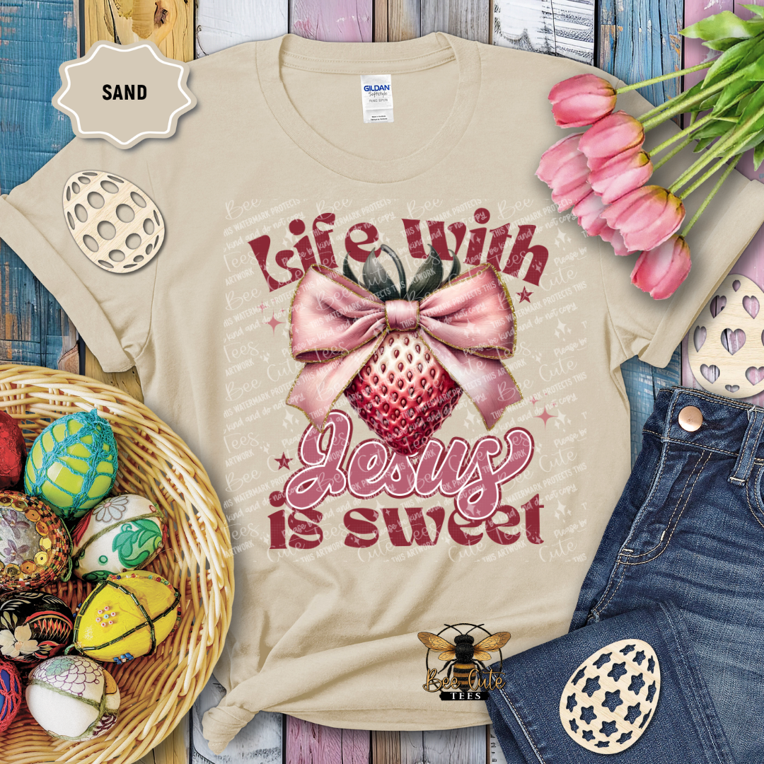 Beige t-shirt with 'Life with Jesus is sweet' design, surrounded by Easter decorations on a wooden surface.