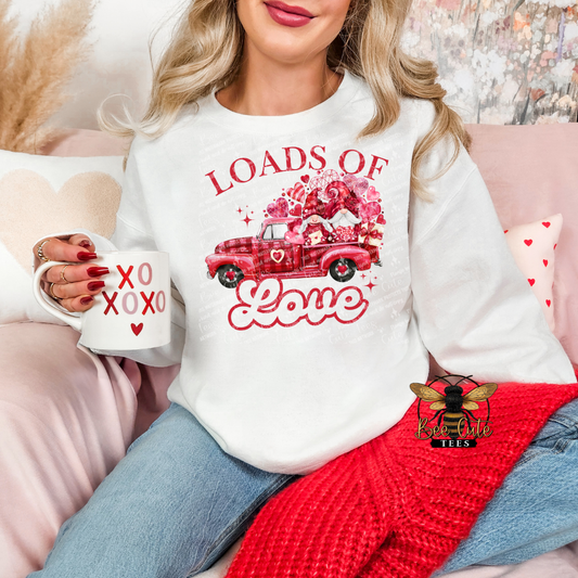 Woman wearing a white sweatshirt with Valentine's Day design, holding a mug, sitting on a pink couch.