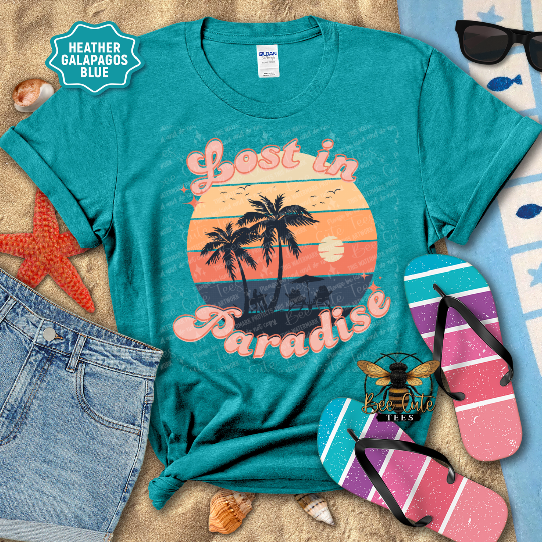Teal t-shirt with 'Lost in Paradise' design on a beach-themed background with sunglasses, flip-flops, and beach accessories.