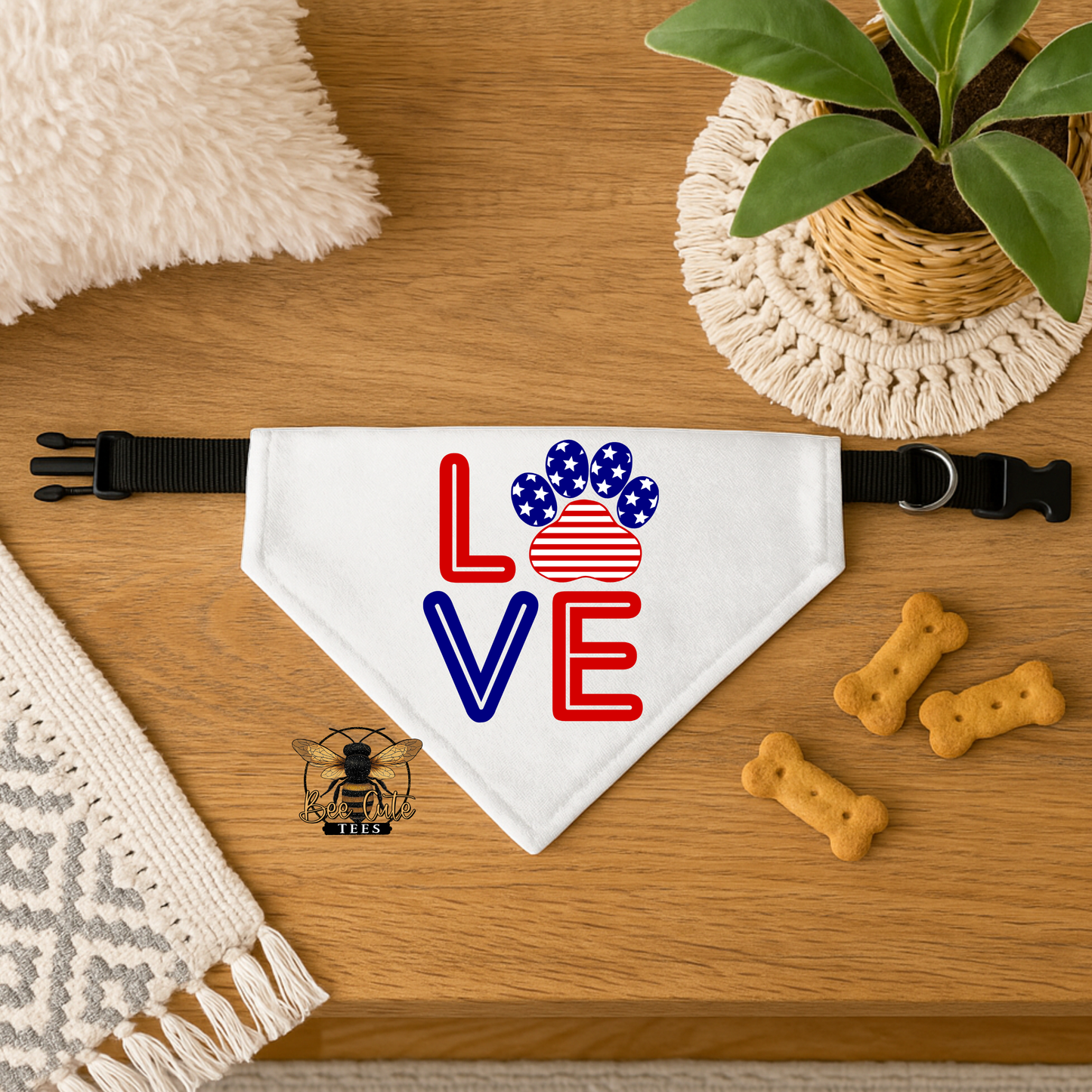 Dog bandana with 'LOVE' and paw print design on a wooden surface with treats and a plant.